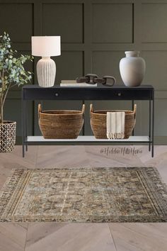 Entryway decor mood board with a dark green accent wall! This sleek black console table has storage baskets underneath to provide extra hidden storage