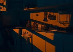 the kitchen is dimly lit by the sun's shadow on the counter top and cabinets