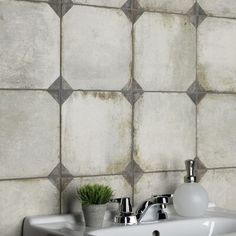 a white sink sitting under a bathroom mirror next to a wall mounted faucet