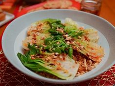 a white bowl filled with food sitting on top of a red tablecloth covered table