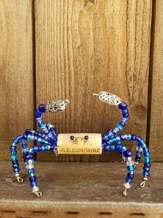 a blue beaded spider sculpture sitting on top of a wooden table next to a bottle opener