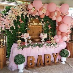 a baby shower with balloons, flowers and greenery on the wall behind the table