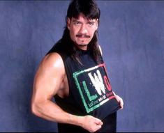 a man with long hair and a moustache holds up a t - shirt