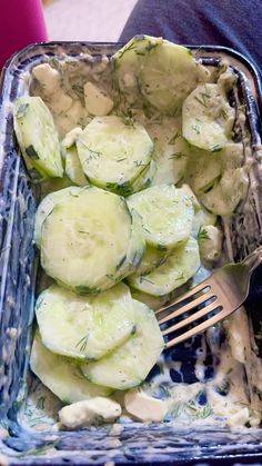 cucumbers and cream in a glass dish with a fork