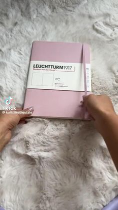 a person holding a pink book on top of a white rug with the words leuchturm 1017