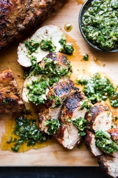 grilled pork chops with pesto sauce on a cutting board