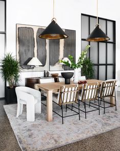 a dining room table with chairs and two hanging lights