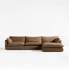 a large sectional couch with pillows on the top and bottom, sitting in front of a white wall