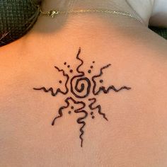 the back of a woman's neck with a tattoo design on her left shoulder