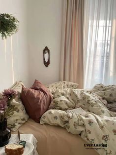 an unmade bed in a bedroom next to a window