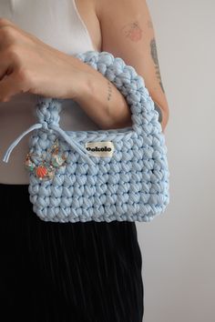 a woman is holding a crocheted blue purse