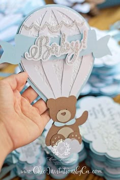 a person holding up a teddy bear in a hot air balloon with the word baby on it