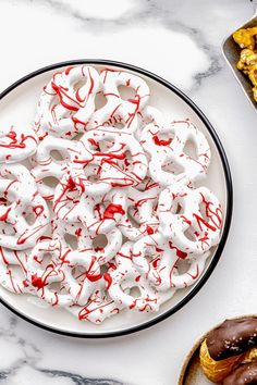 a white plate topped with donuts covered in red and white icing next to other pastries