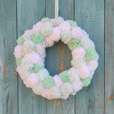 a wreath hanging on the side of a wooden door decorated with pom - poms