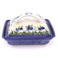 a blue and white ceramic covered dish with flowers on the front, sitting on a white surface