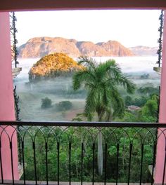 a balcony with a view of mountains, trees and fog in the distance on a cloudy day