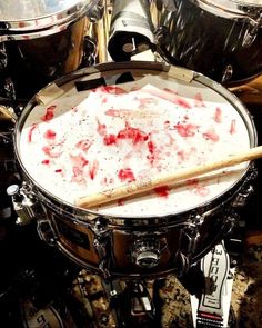 a drum with blood on it sitting next to two cymbals and drumsticks