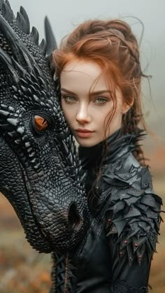 a woman with red hair is holding a black dragon in her hands and wearing leather clothes