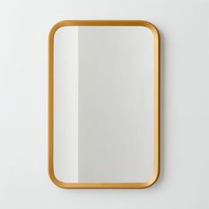 a square mirror on the wall with a gold rim around it and a white background