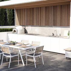 an outdoor kitchen and dining area with wooden slats on the wall, white table and chairs