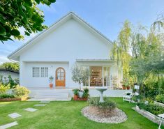 a white house sitting on top of a lush green field