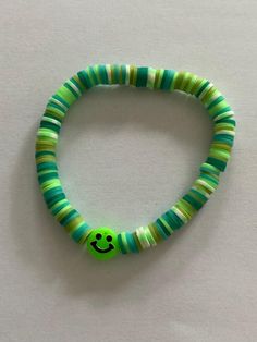 Colourful bracelet in shades of green with a smiley face Green Bangle Friendship Bracelets, Cute Green Round Bead Jewelry, Green Round Beaded Bracelets For The Beach, Playful Green Beaded Bracelet As A Gift, Trendy Green Bracelets For Friendship, Playful Green Round Jewelry, Fun Green Bracelets For Friendship, Fun Green Beaded Bracelets For Friendship, Playful Green Beaded Bracelets