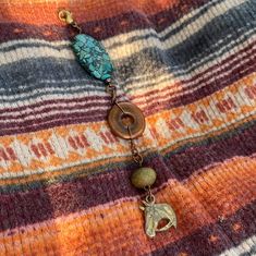 a close up of a necklace on a blanket with beads and an elephant charm hanging from it