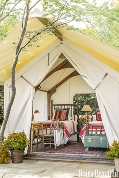 two beds in a tent with curtains on the top and one bed sitting under a tree