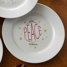 three white plates sitting on top of a wooden table with christmas decorations painted on them