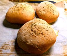 three bread rolls sitting on top of a piece of wax paper