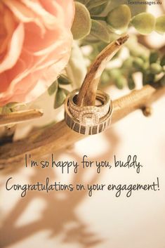 a wedding ring sitting on top of a wooden branch with flowers in the background and text that reads, i'm so happy for you, buddy congratulationss our engagement