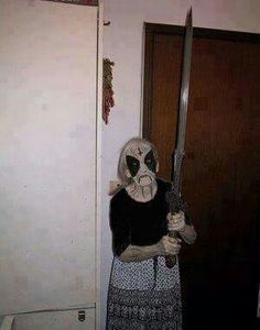 a person in a costume holding a knife and wearing a mask while standing next to a door