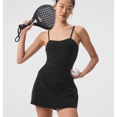 a woman holding a tennis racquet in her right hand and wearing a black dress