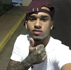 a man with tattoos on his arm and hand pointing to the side while wearing a hat