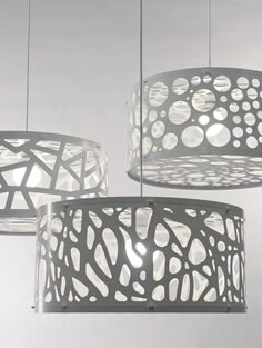 three lamps hanging from the ceiling with circles and dots on them, one is white