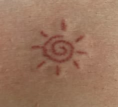 the back of a person's neck with a sun tattoo on it and red ink