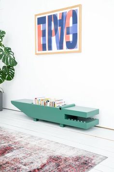 a green coffee table sitting on top of a white floor next to a potted plant