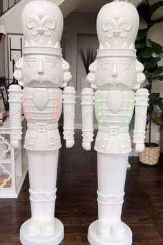 two white plastic robot statues sitting on top of a wooden floor