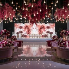 an elegant wedding set up with pink flowers and candles hanging from the chandelier