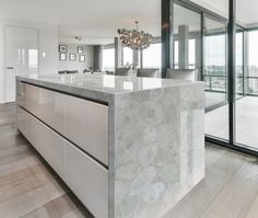 a large kitchen with marble counter tops and stainless steel appliances in front of sliding glass doors