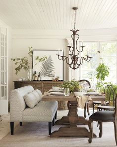 a living room filled with furniture and a chandelier hanging from the ceiling over a dining table