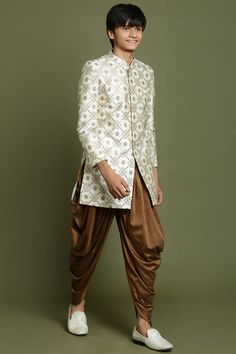 YUVA By VASTRAMAY Boys Beige And Coffee jacquard Sherwani Set Dress your young man in sophisticated style with this Vastramay Yuva Boys' Sherwani Set. The beige jacquard sherwani features a mandarin collar, long sleeves, and side slits for a classic look. It pairs perfectly with the coffee-colored dhoti pants for a complete and comfortable outfit. Features: Beige jacquard sherwani with mandarin collar Long sleeves Side slits Coffee-colored dhoti pants with elasticated waistband Specifications: Top fabric: Woven Bottom fabric: Viscose Sleeve Length: Long Top Shape: Straight Material & Care: Dry clean only. Legal Disclaimer: The product is guaranteed to be 100% genuine. Product images are for illustrative purposes only. Images/packaging/ labels may vary from time to time due to changes made Dhoti Style Dresses, Boys Sherwani, Comfortable Outfit, Boys Wear, Sleeveless Jacket, Full Sleeves, Packaging Labels, Top Fabric