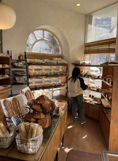 a woman standing in front of a counter filled with bread