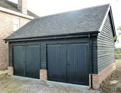 two black garages in front of a brick building with an open door on the side