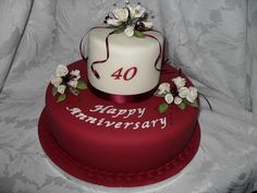 a red and white birthday cake with flowers on the top that says 40 happy anniversary