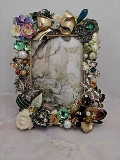 an ornate photo frame with flowers and pearls on the front, sitting on a marble surface