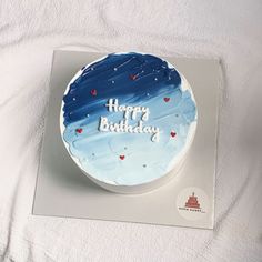 a birthday cake with blue frosting and hearts on it sitting on a white surface