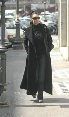 a woman is walking down the street in her coat