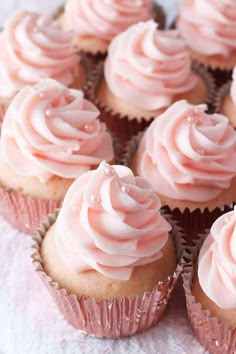 cupcakes with pink frosting sitting on a napkin