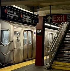 a subway train parked at the station with its doors open and stairs leading up to it